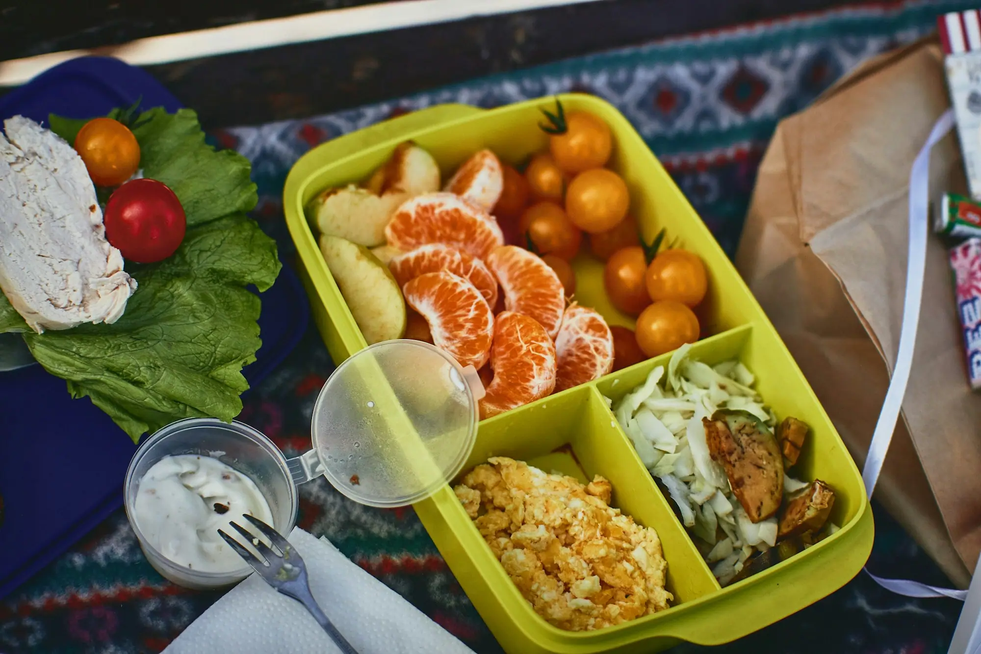 A bright lunchbox with orange segments, cherry tomatoes and rice