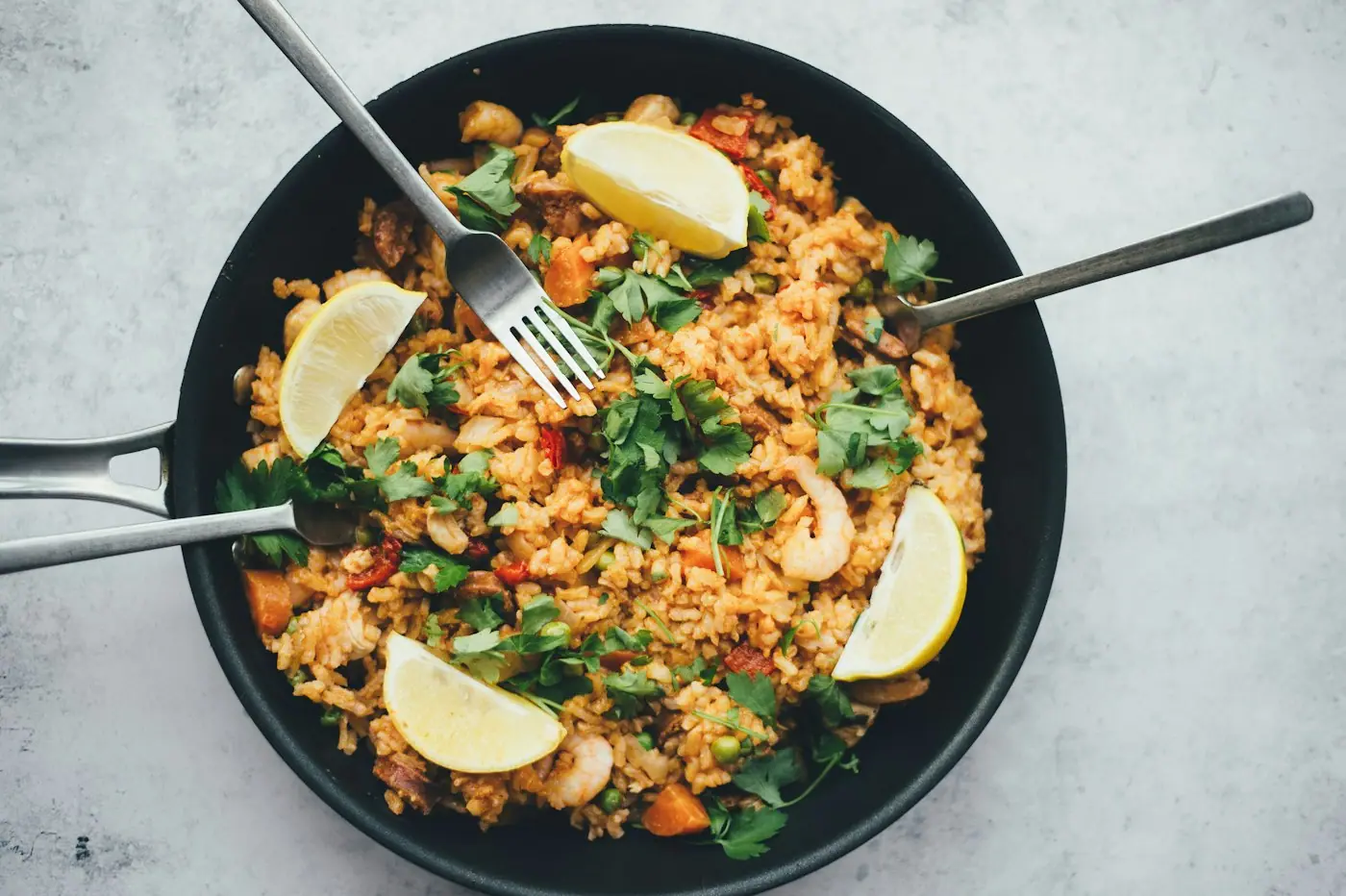 A one-pan rice dish with lemon wedges in a black skillet